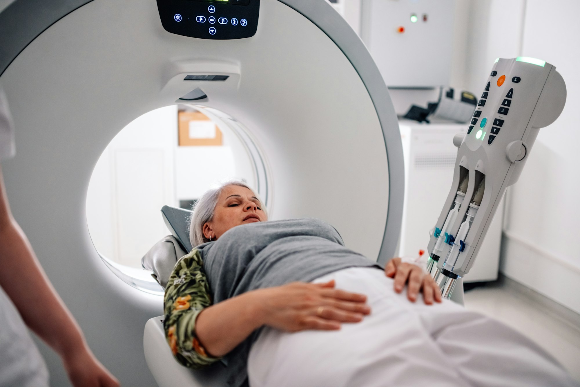 Woman preparing for a CT scan in a medical imaging machine room.